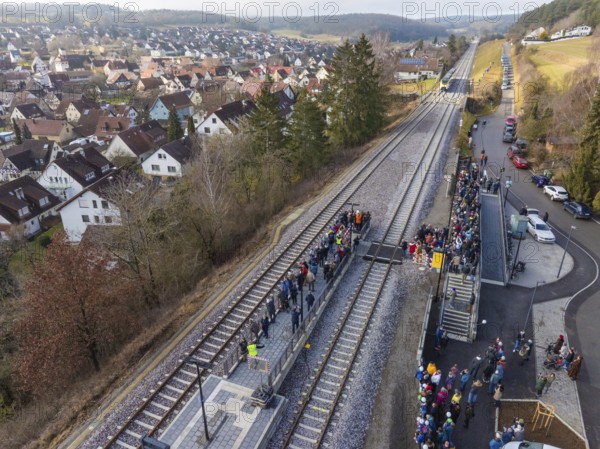 View of railway line with people next to an urban housing estate in a hilly landscape, opening of the Hermann Hesse Railway, Calw, Germany
