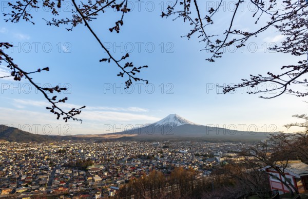 View of Mount Fuji volcano over Fujiyoshida City in evening light, at sunset, Arakurayama Sengen Park, Yamanashi Prefecture, Japan