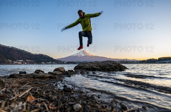 Young man jumping, Lake Kawaguchi, view of Mount Fuji volcano at sunset, Yamanashi Prefecture, Japan