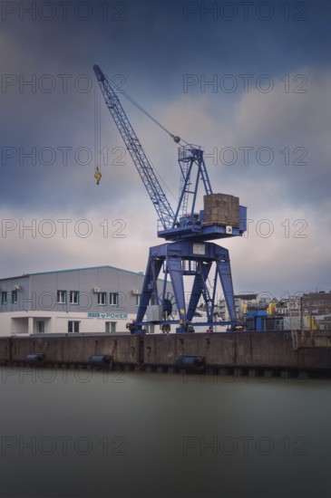 View of a crane standing directly at a harbor basin, Bremerhaven, Bremen, Germany