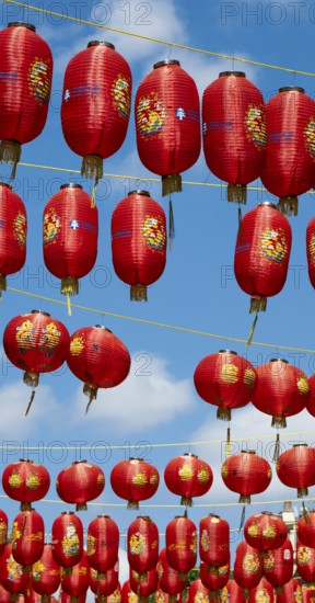 Red Chinese lanterns hanging on yellow lines against a blue sky, London, England, Great Britain