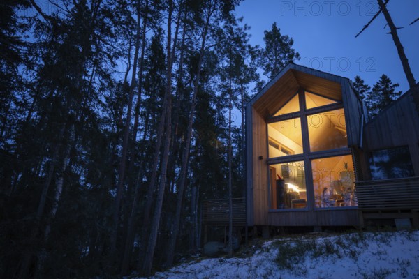 Modern wooden house in the forest, illuminated from within and inviting at dusk, Korpoström, Korpo or Korppo, southwestern archipelago, Finland
