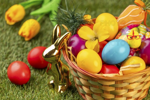 A basket with colorful eggs, flowers and Easter decoration in a meadow