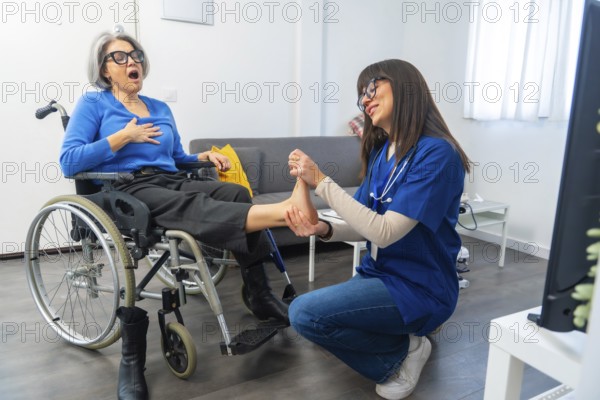 Elderly woman in a wheelchair receiving physical therapy from a caregiver, focusing on her foot and ankle for mobility and wellness in a home care setting