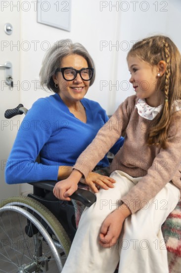 Granddaughter tenderly interacting with her smiling grandmother in a wheelchair, symbolizing strong family bonds, intergenerational love, and compassionate care during a visit