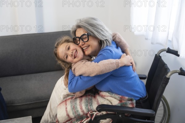 Granddaughter embracing elderly grandmother with gray hair and glasses. Sitting in a wheelchair. Sharing a tender moment of affection and intergenerational connection during a home visit or daily care
