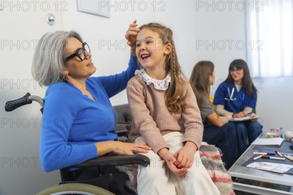 Granddaughter laughing while visiting her grandmother in a wheelchair, sharing a heartwarming moment together in a care facility room, highlighting family support and intergenerational connection