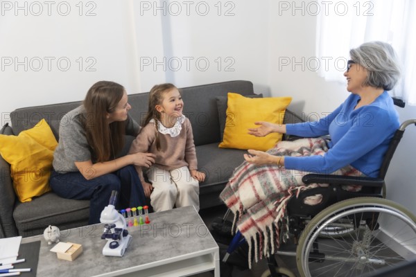 Three generations of family members warmly interacting, an elderly woman in a wheelchair engaging with her daughter and granddaughter on a couch, creating a loving and supportive domestic scene