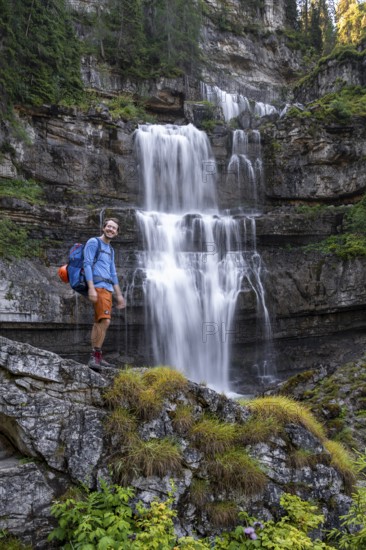Hiker standing in front of Cascata di Mezzo waterfall, long exposure, Vallesinella, Brenta, Trentino, Italy
