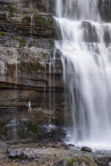 Little hiker in front of large Cascata di Mezzo waterfall, long exposure, Vallesinella, Brenta, Trentino, Italy