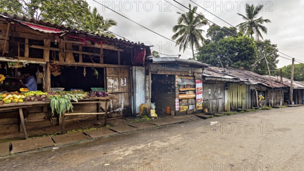 Abandoned street market area with wooden huts and tropical palm trees, small shops on the side of a road in the mountains near Kandy Sri Lanka