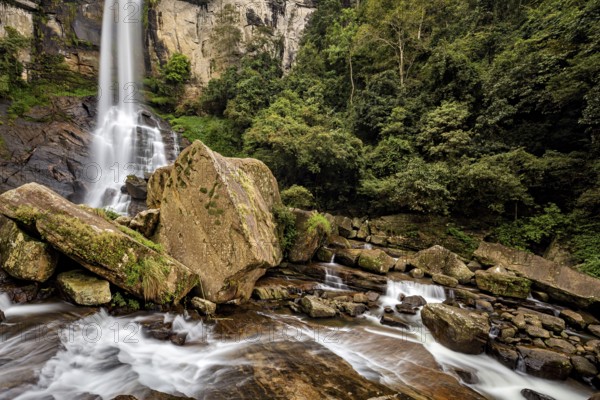 A large waterfall in the jungle surrounded by massive rocks and lush greenery, waterfall in the mountains of Kandy in Sri Lanka