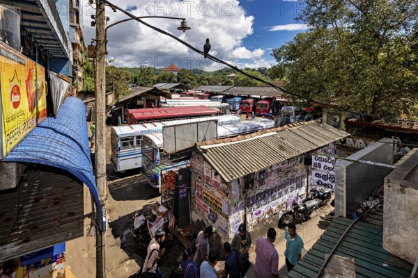 View of a depot densely staffed by buses, surrounded by billboards and trees, Kandy bus station in Sri Lanka