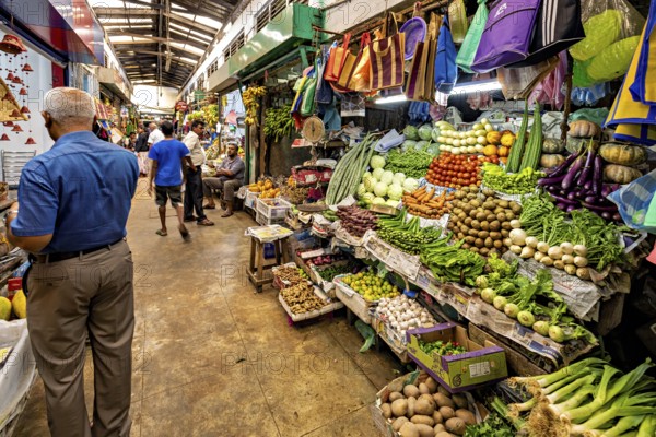 Market stall with a plethora of fresh vegetables and people shopping, The old market halls of Kandy in Sri Lanka