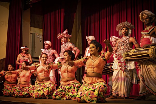 Dancers in colorful, traditional costumes dance with drummers on a stage, folklore and dancers from the famous Kandy Dance in Kandy in Sri Lanka
