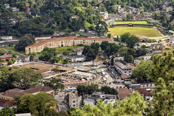View of a historic fortress and a market square in an urban environment with lots of greenery, view of the city center of Kandy in Sri Lanka
