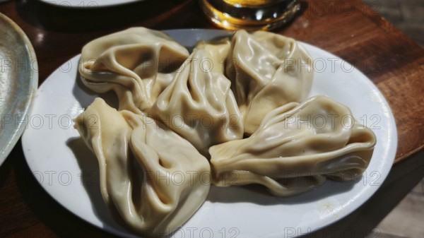 Delicious stuffed dumplings, Georgian cuisine, khinkali on a white plate, served on a wooden table, Georgia