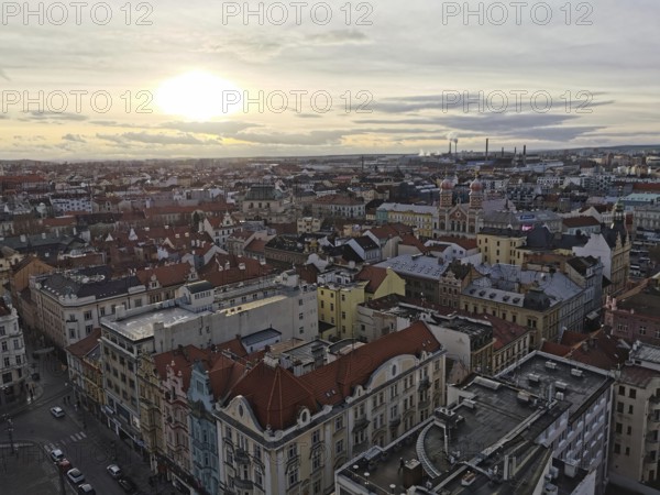 Extensive view of urban rooftops at sunset with industry on the horizon, Pilsen, Czech Republic