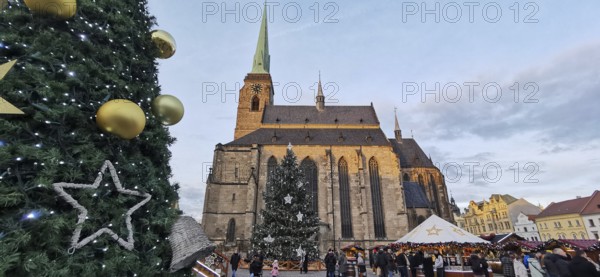 Christmas market in front of a big church with festive decoration and people, Pilsen, Czech Republic