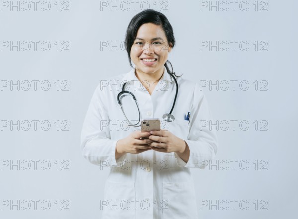 Young asian female doctor holding phone looking at camera isolated, Concept of online medical services