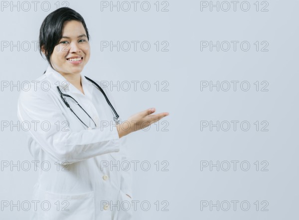 Young asian doctor presenting something isolated. Smiling asian female doctor showing empty space