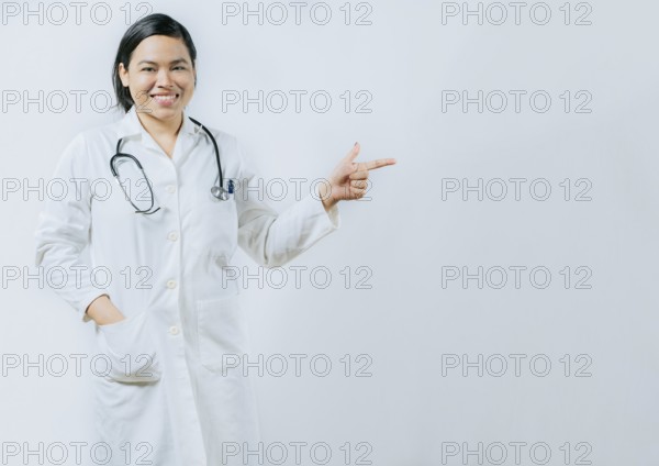 Asian female doctor pointing at medical banner isolated. Young asian female doctor recommending an advertisement