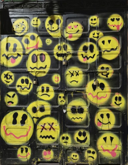 Yellow smiley faces on a dark metal door as graffiti, Morocco
