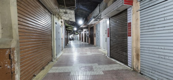 Medina during prayer time in Ramadan, empty, nocturnal alley with closed shops and rolling metal gates, Morocco