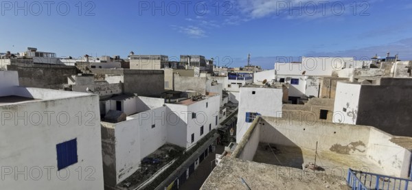 View over the rooftops of an old town with white buildings and blue sky, southern Morocco