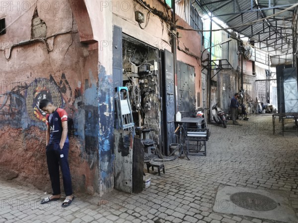 Boy in an abandoned urban workshop with grey walls, metallic, atmospheric, Medina, Morocco