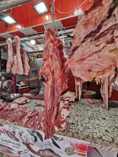 Close-up of pieces of meat and camel's head (camelum) at a lively butcher's stall with red décor, southern Morocco