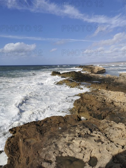 Thundering waves hitting rocky coast under blue sky, Morocco