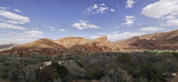 Wide desert landscape with mountains under a slightly cloudy sky, Morocco