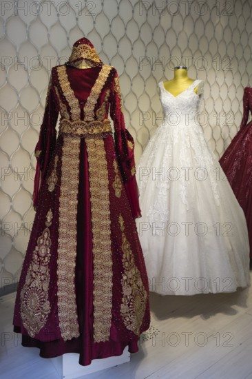 Two magnificent wedding dresses, one red with gold embroidery and one classic white dress, displayed on dolls, Konya, Central Anatolia, Turkey
