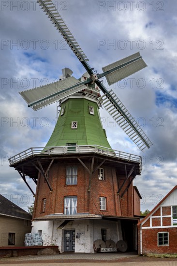 Historic brick windmill with green roof under cloudy sky, An old historic windmill near Stade