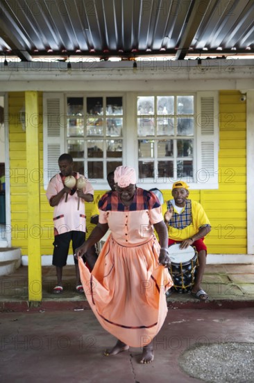 Guatemalan woman in traditional dress singing and dancing, men playing music in the back, Garifuna people, Livingston, Izabal Department, Guatemala