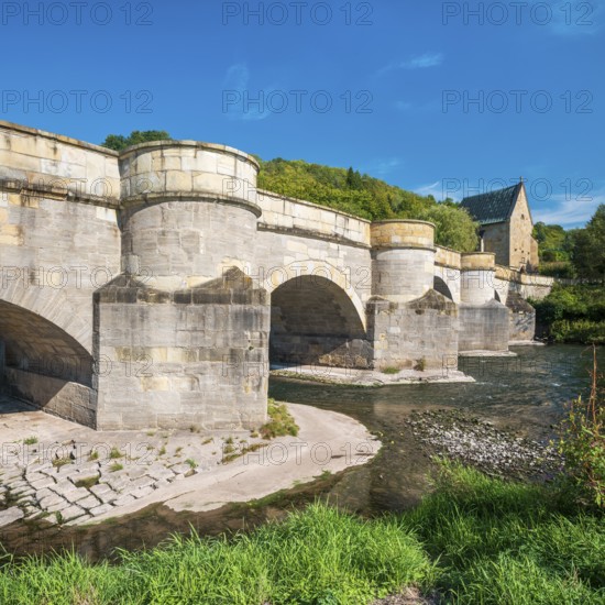 13th century medieval stone bridge across the Werra river, in the back the Liborius chapel, Creuzburg, Thuringia, Germany