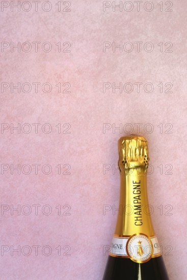 Champagne bottle on pink background, New Year's Eve