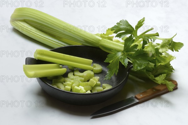 Celery stalks, pieces with knife in pot