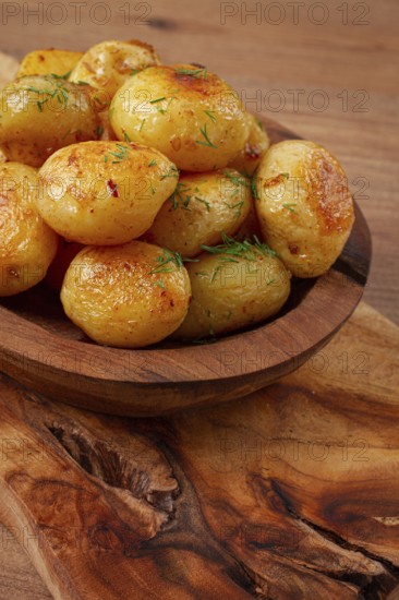 Baked new potatoes, with butter and dill, on a wooden plate, homely, rustic, no people