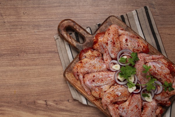 Chicken wings, marinated and laid out on a wooden platter, ready for cooking, grilling or baking, in a home kitchen, there are no people