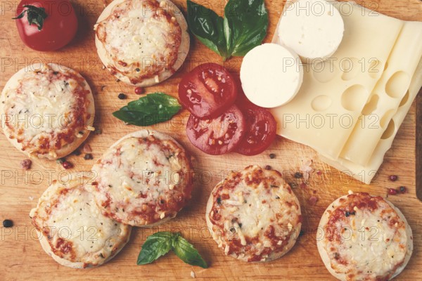 Freshly baked mini pizza, on a wooden board, with fresh vegetables and cheese, top view
