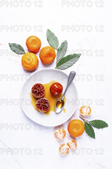 A plate with a spoonful of tangerine jam, fresh tangerines, on a marble table, top view