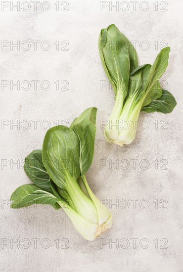 Fresh bok choy, laid out on a light gray surface, top view, natural light