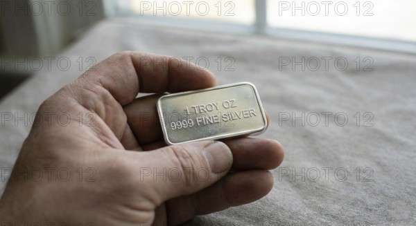 Fine silver bar, with neatly stacked silver bullion bars arranged behind it, symbolising precious metal investment, wealth preservation, and commodity trading, AI generated
