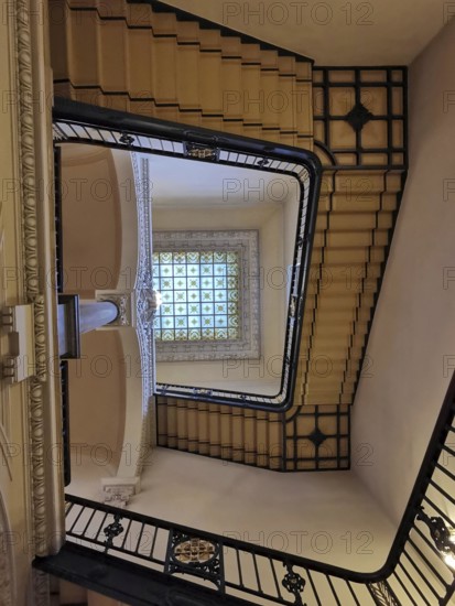 Historic staircase with artfully designed railing and glass window on the ceiling, Berlin, Germany