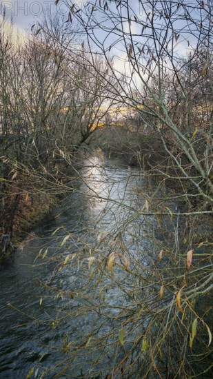 Cool river landscape in winter with leafless trees and calm water, Franconian Forest, Germany