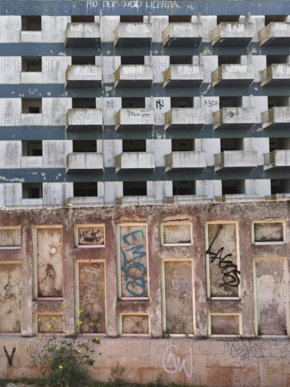 Abandoned building with graffiti on a dilapidated façade and blue, white, textured concrete architecture in an urban environment