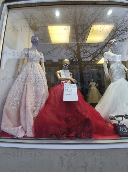Shop window with festive clothes and mannequins wearing masks during corona, elegant ambiance, Berlin