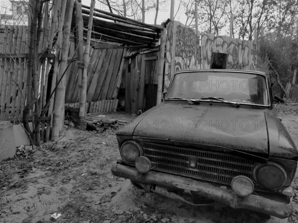 Abandoned old car in front of a dilapidated building with graffiti, Berlin, Germany